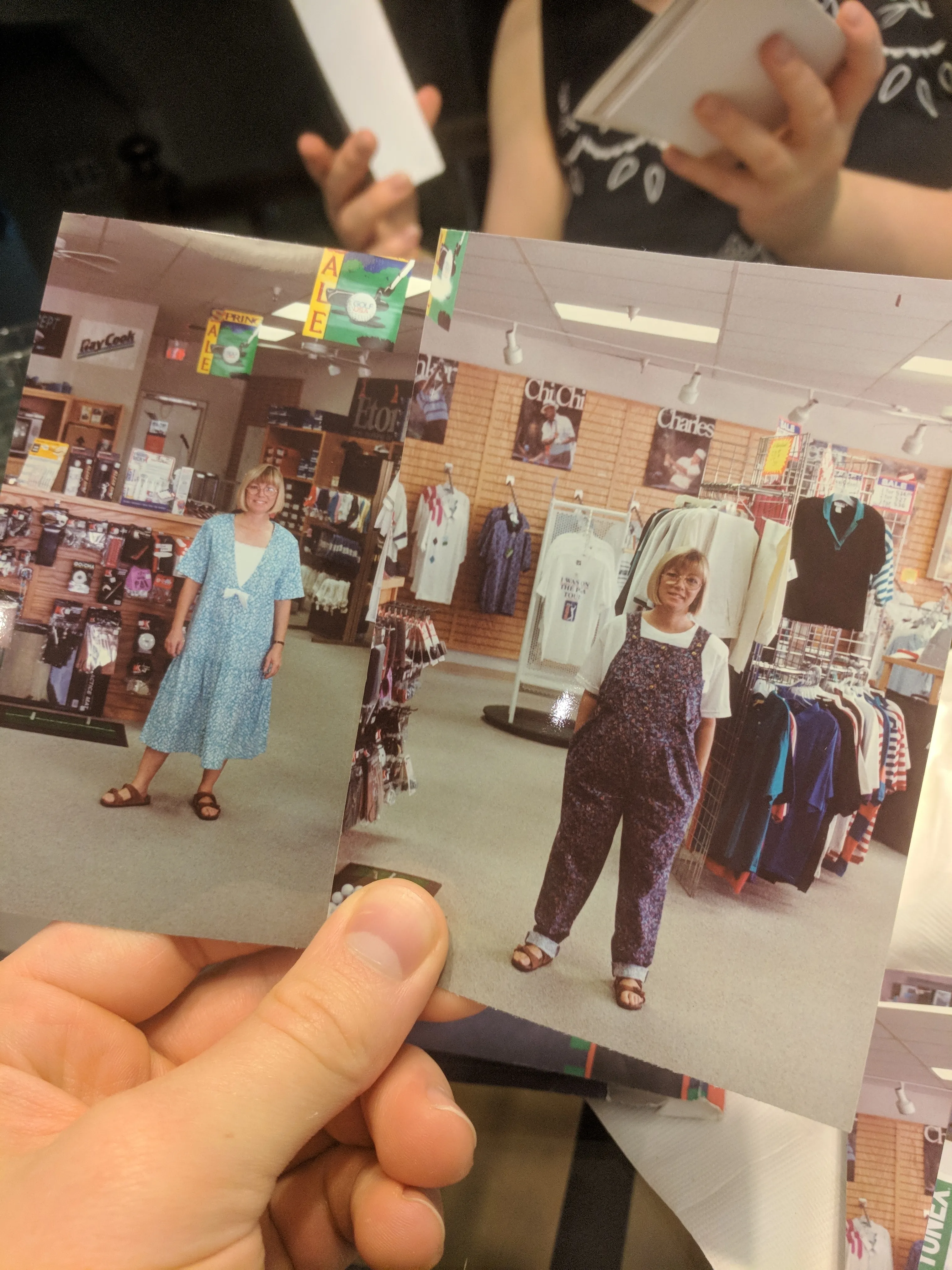 A hand holding two old printed photographs of a young Suzanne in a golf shop