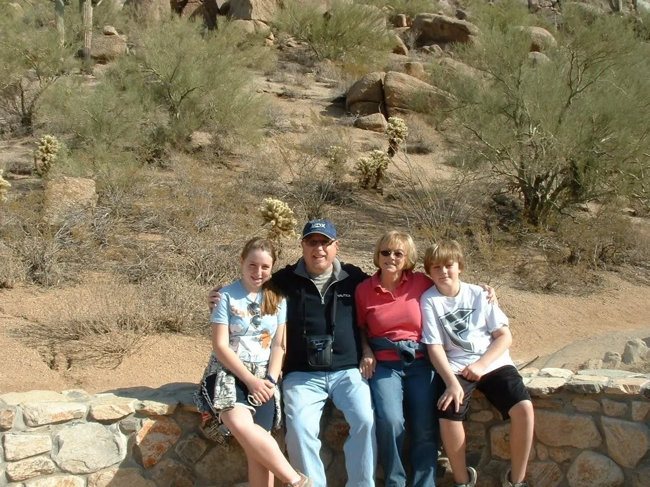 Suzanne and Ray with their two children, sitting on a stone wall in the desert